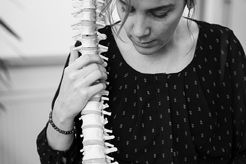 Osteopaat Martius met het model van een ruggengraat. Daarmee legt ze uit hoe ze lage rugklachten behandelt